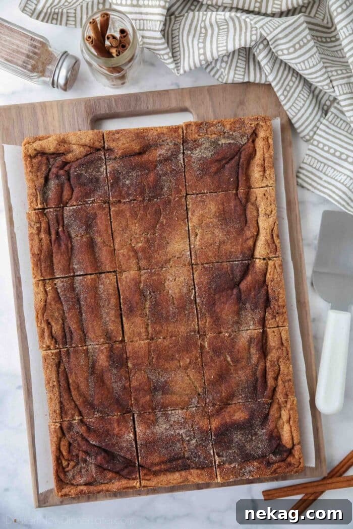 Chewy Cinnamon Bars with Brown Sugar Glaze 3 Cinnamon Bars cut into squares on a wooden cutting board.