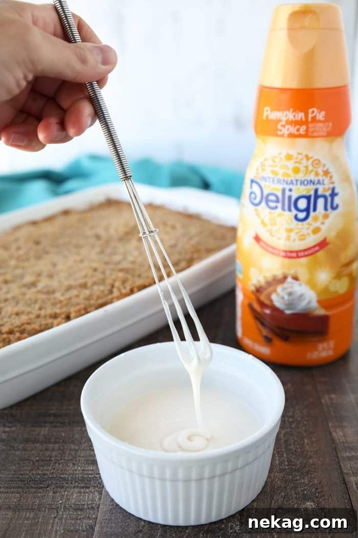 Pumpkin Spice Coffee Cake Recipe: Moist Autumn Coffee Cake 7 Glaze made with powdered sugar and International Delight Pumpkin Pie Spice Coffee Creamer dripping from a whisk.