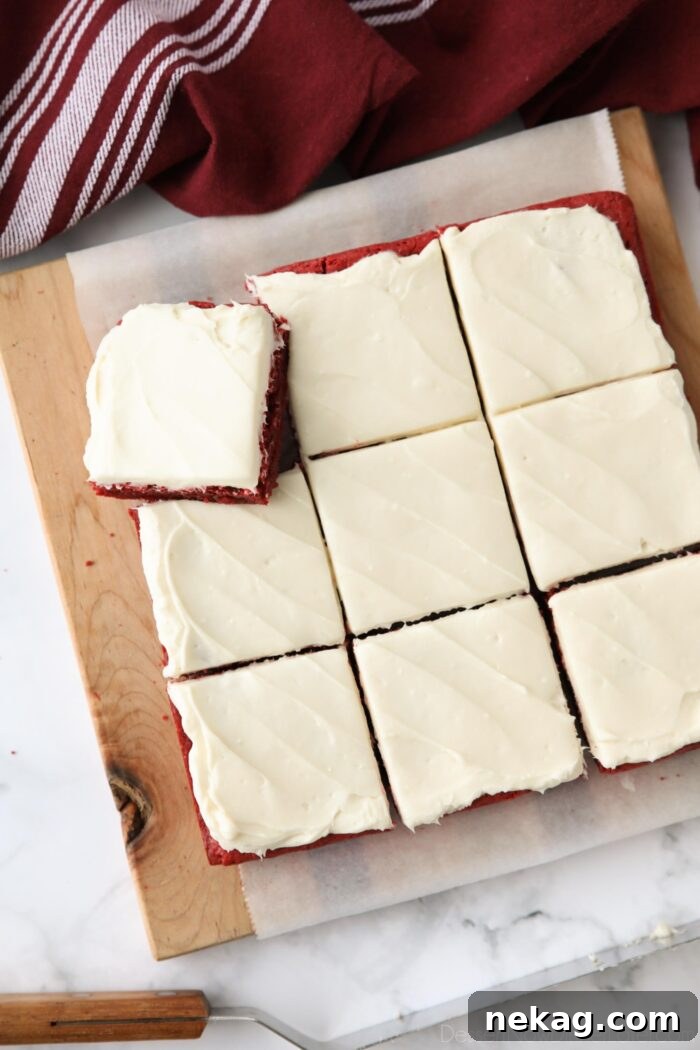 Decadent Red Velvet Brownie Recipe with Cream Cheese Swirl 3 Square pan of Red Velvet Brownies with cream cheese frosting cut into squares on a cutting board.