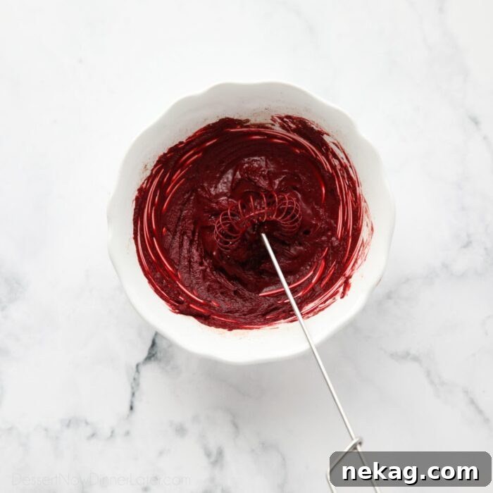 Decadent Red Velvet Brownie Recipe with Cream Cheese Swirl 5 Red cocoa paste in a bowl with a whisk.