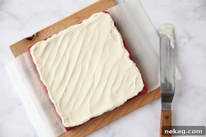 Decadent Red Velvet Brownie Recipe with Cream Cheese Swirl 9 Cream cheese frosting spread on top of red velvet brownies.