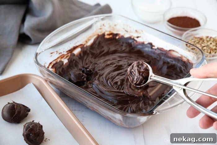 Decadent Chocolate Truffle Recipe: Homemade Rich Truffles in Minutes 7 Chilled chocolate ganache is scooped for truffles and placed on a tray with parchment paper.