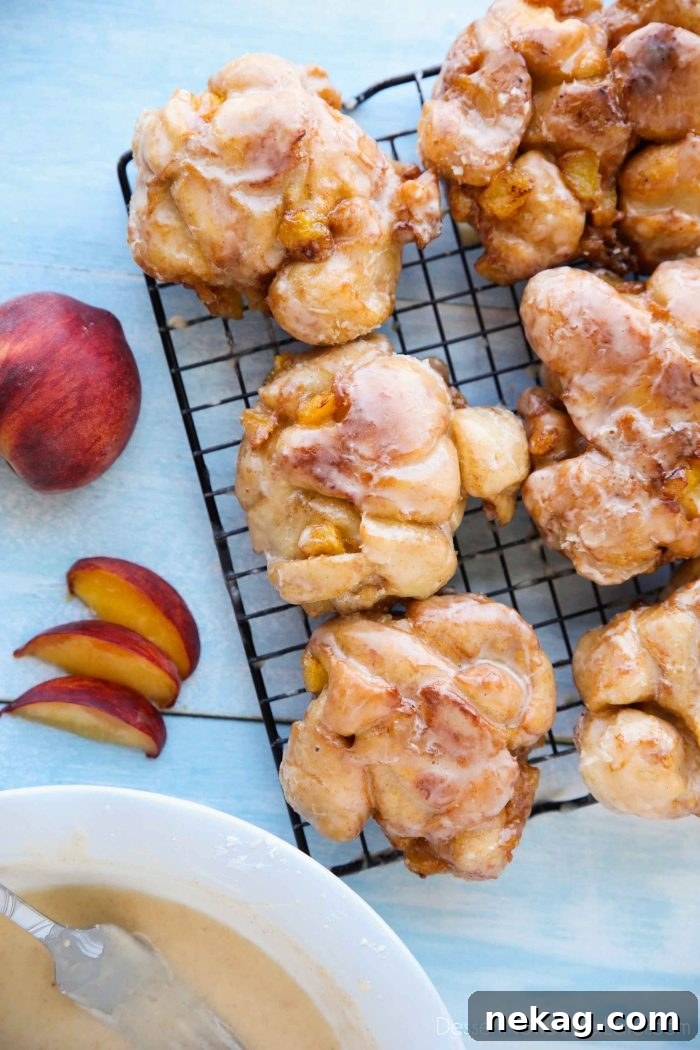 Glazed Peach Fritters Donuts on a cooling rack.