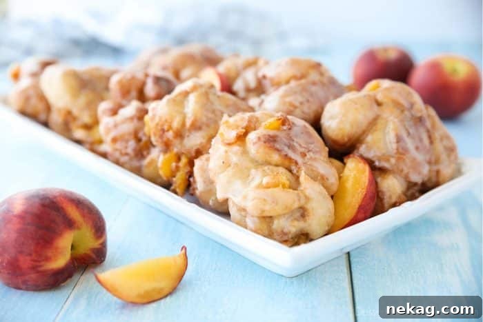 Glazed Peach Fritters Donuts on a platter with fresh peaches.