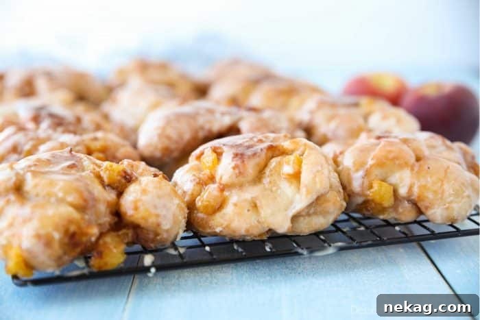 Glazed Peach Fritters Donuts on a cooling rack.