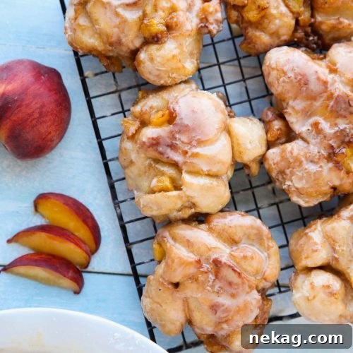 Glazed Peach Fritters Donuts on a cooling rack.