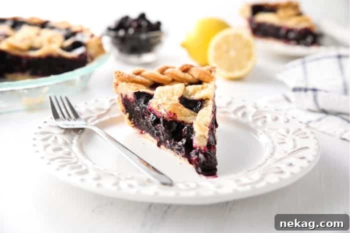Slice of easy homemade blueberry pie on a plate with a fork.