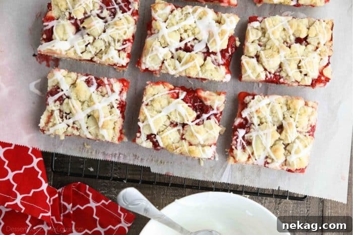 Cherry pie bars on top of parchment paper and a cooling rack.