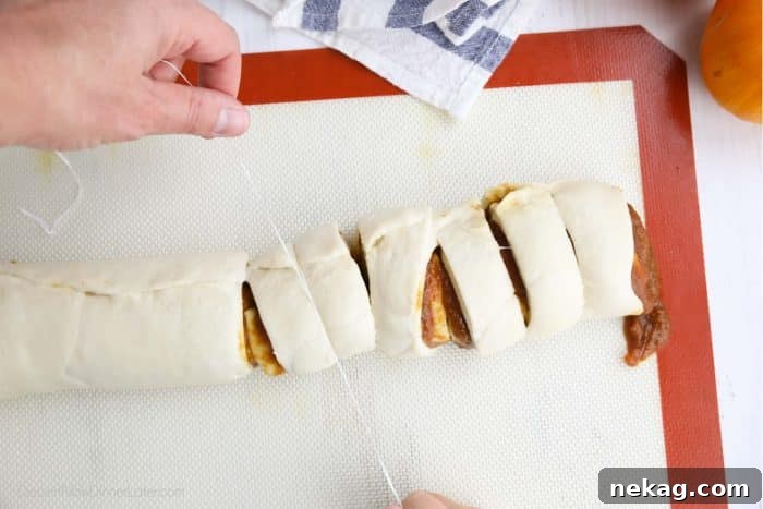 Pumpkin Spice Cinnamon Rolls with Cream Cheese Glaze 8 Pumpkin pie cinnamon rolls being cut with floss.