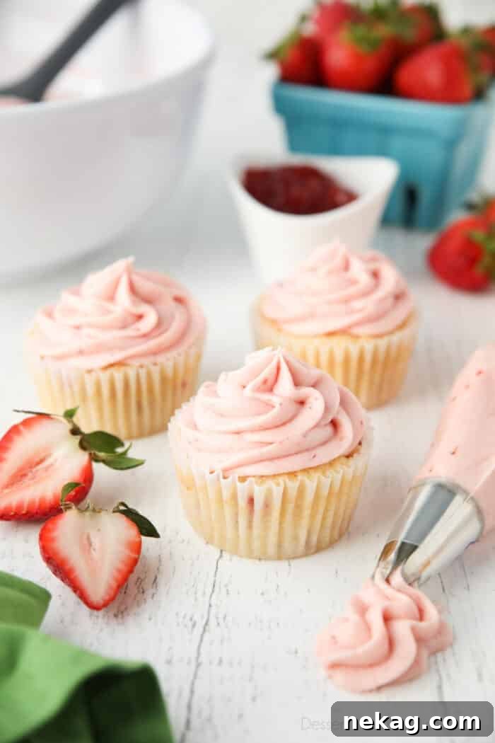 Strawberry frosting piped onto cupcakes.