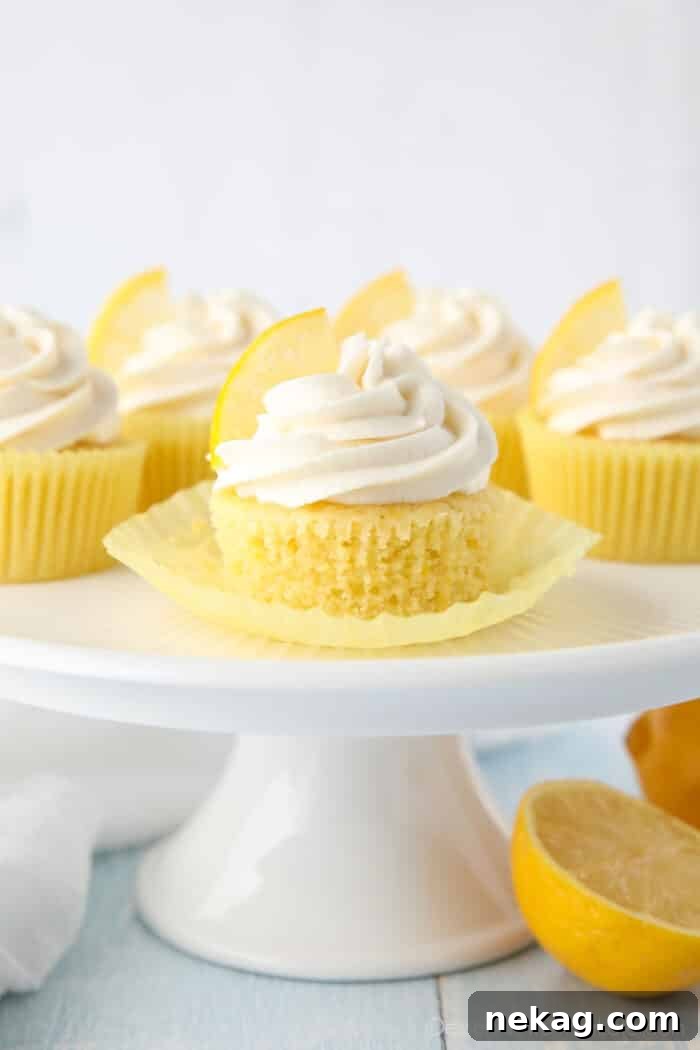 Side view close-up shot of lemon cupcake with wrapper peeled down to show fluffy texture.