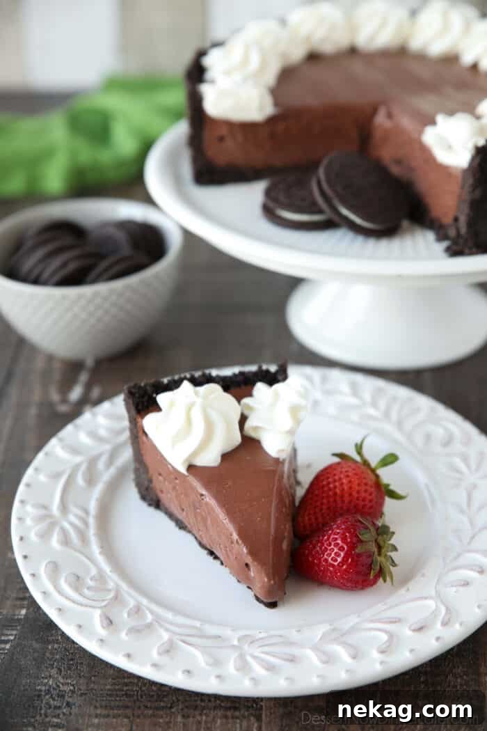 Slice of no bake cheesecake with whipped cream piped on top and strawberries on the side.