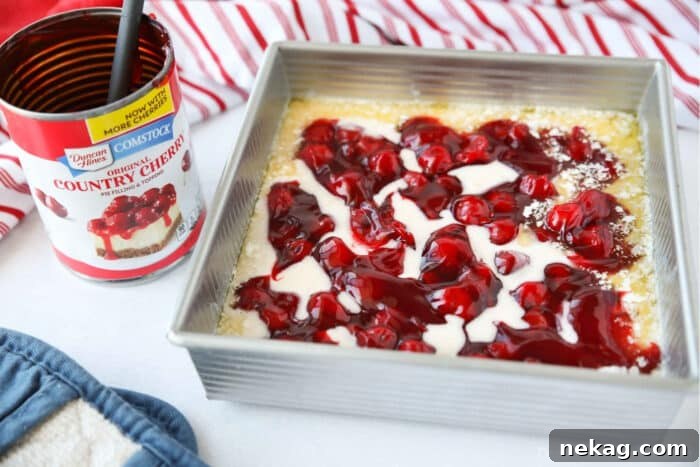 Classic Cherry Cobbler Recipe with Golden Biscuit Topping 9 Cake batter and cherry pie filling on top of melted butter before baking.