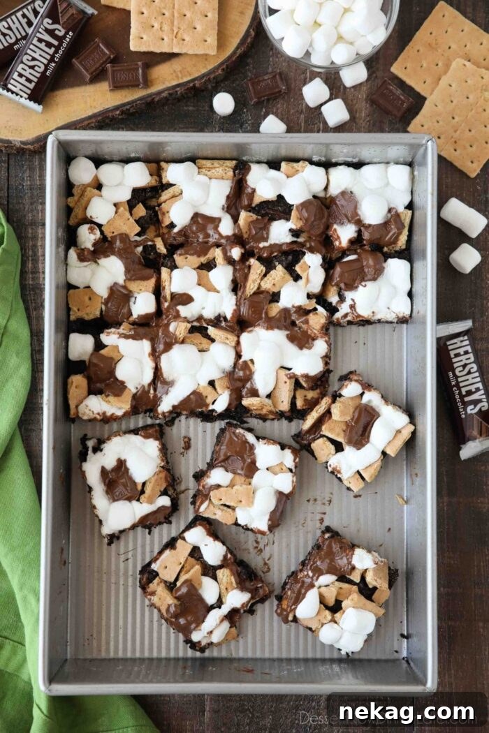 S'mores Brownies Recipe: Gooey Chocolate Graham Bar Squares 2 S'mores Brownies with graham crackers, mini marshmallows, and Hershey's chocolate bars in a pan, cut into squares with a few missing, and other brownies separated from the rest.