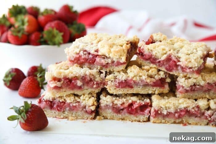 Chewy Strawberry Crumb Bars with Perfect Jam Layer 11 Strawberry Crumb Bars stacked on top of parchment paper.