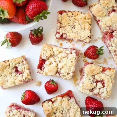 Chewy Strawberry Crumb Bars with Perfect Jam Layer 12 Strawberry Crumb Bars cut into squares with fresh strawberries.