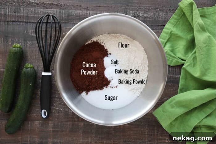 Moist Chocolate Zucchini Muffins with Melted Chocolate Chips 6 Bowl of labeled ingredients for chocolate zucchini muffins: Flour, Sugar, Cocoa Powder, Salt, Baking Soda, and Baking Powder.