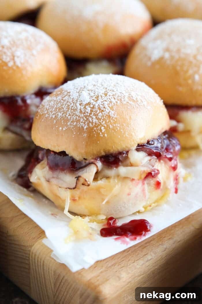 Crispy Monte Cristo Sliders with Ham, Turkey & Melty Cheese 4 Close up of ham, turkey, and Swiss cheese mini sandwiches with raspberry preserves.