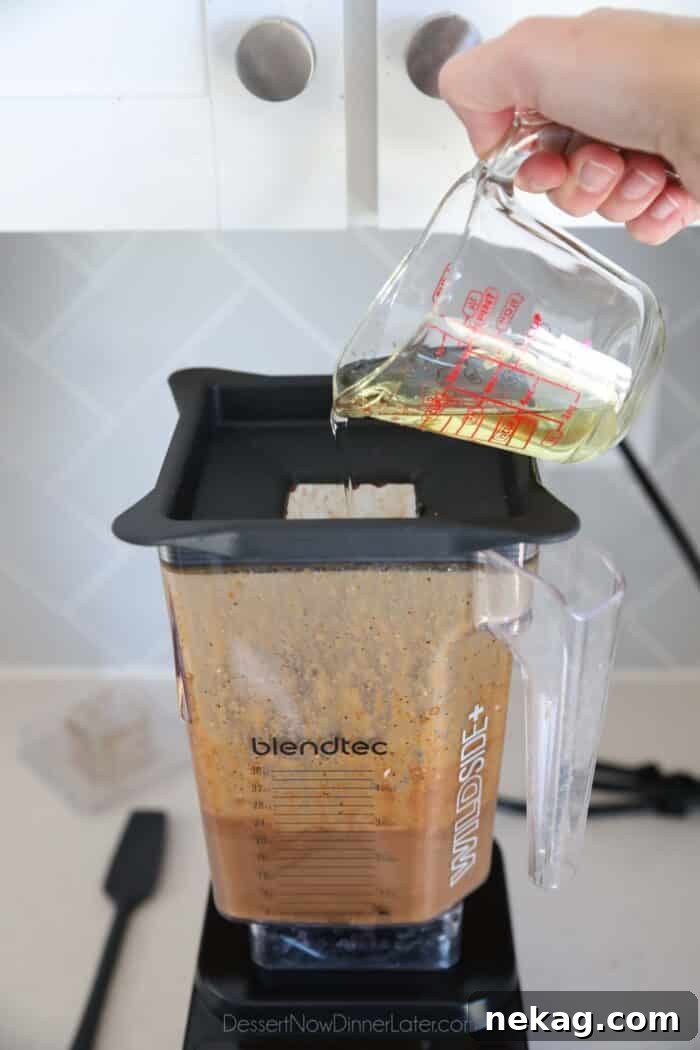 Slowly adding oil to blender of ingredients for balsamic dressing.