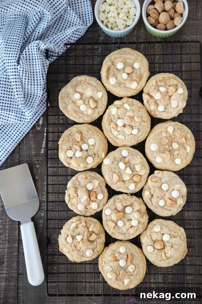 White Chocolate Macadamia Nut Cookie Recipe for Chewy Crispy Cookies 4 White Chocolate Macadamia Nut Cookies on a cooling rack with a spatula on the side.