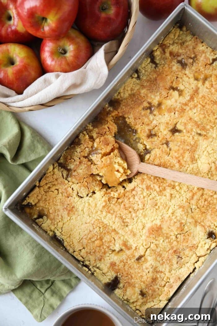 Baking pan with a spoon scooping up some caramel apple dump cake.