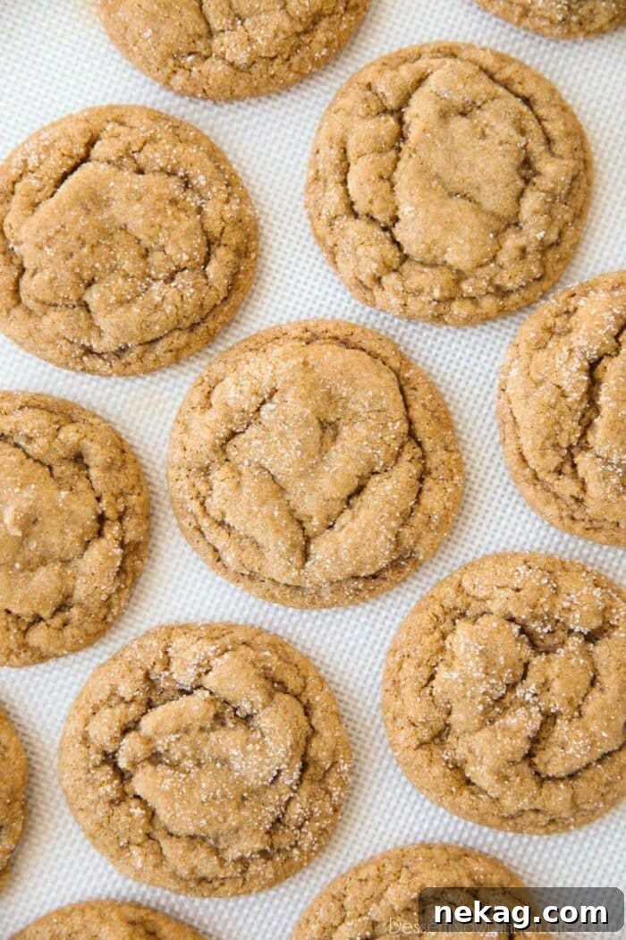 Chewy Pumpkin Gingersnap Cookies with Warm Spices 4 Baked pumpkin gingersnap cookies on a silicone baking mat.
