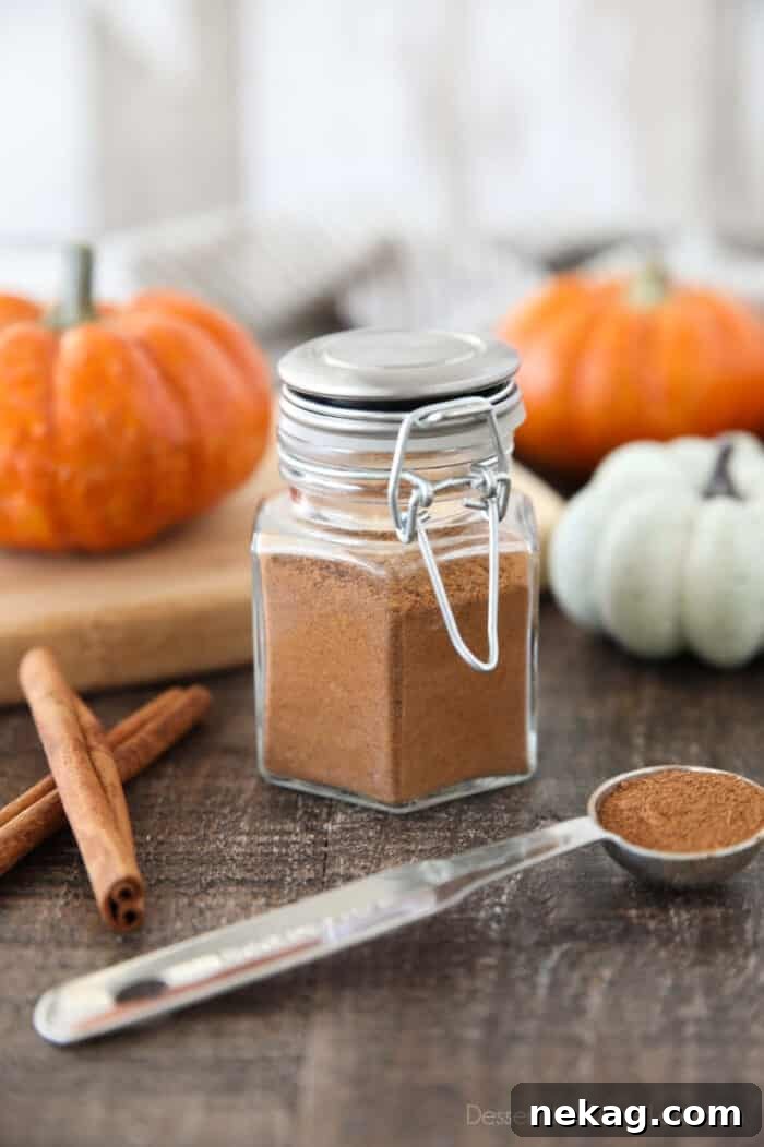 How to Make Homemade Pumpkin Pie Spice Blend for Fall Baking 2 Homemade Pumpkin Pie Spice in a glass jar with mini pumpkins and cinnamon sticks on the side.
