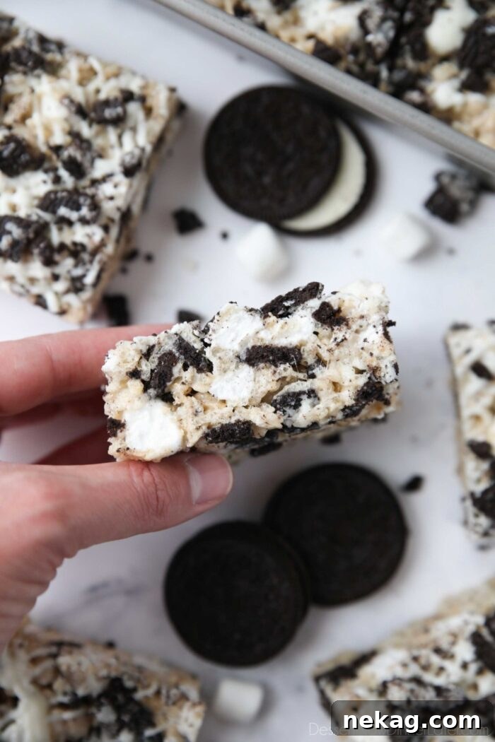 Oreo Rice Krispie Treats Recipe: Chewy Chocolate Marshmallow Squares 3 Holding a rice krispie treat with Oreos.