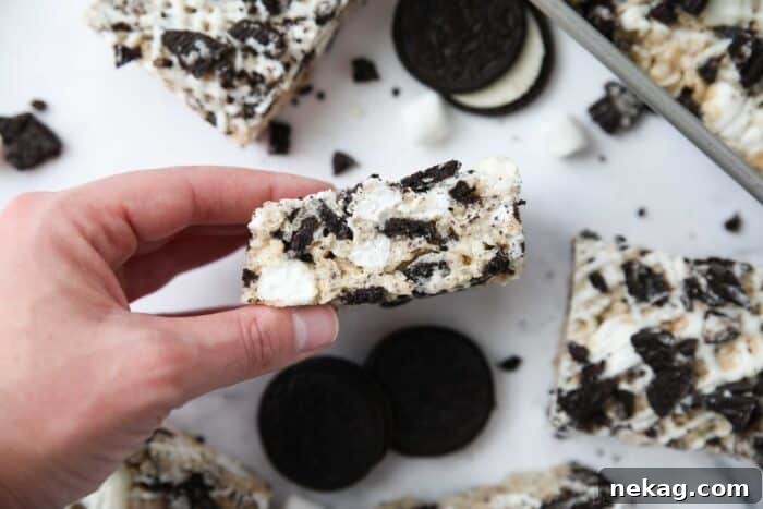 Oreo Rice Krispie Treats Recipe: Chewy Chocolate Marshmallow Squares 10 Holding a rice krispie treat with Oreos.