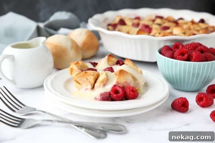 Creamy Raspberry Bread Pudding Recipe with Vanilla Sauce 11 Bread pudding on plate with raspberries and vanilla sauce.