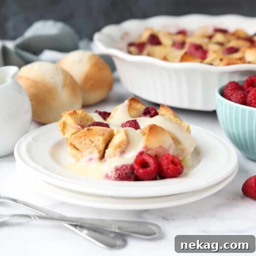Creamy Raspberry Bread Pudding Recipe with Vanilla Sauce 13 Bread pudding on plate with raspberries and vanilla sauce.