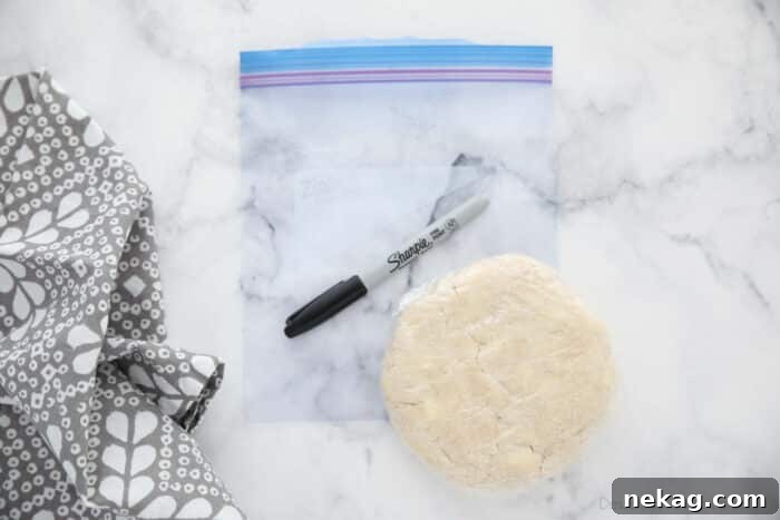 Flaky All-Butter Pie Crust Recipe for Perfect Pastry 11 Pie crust wrapped in plastic wrap on top of a freezer bag with a sharpie for labeling.