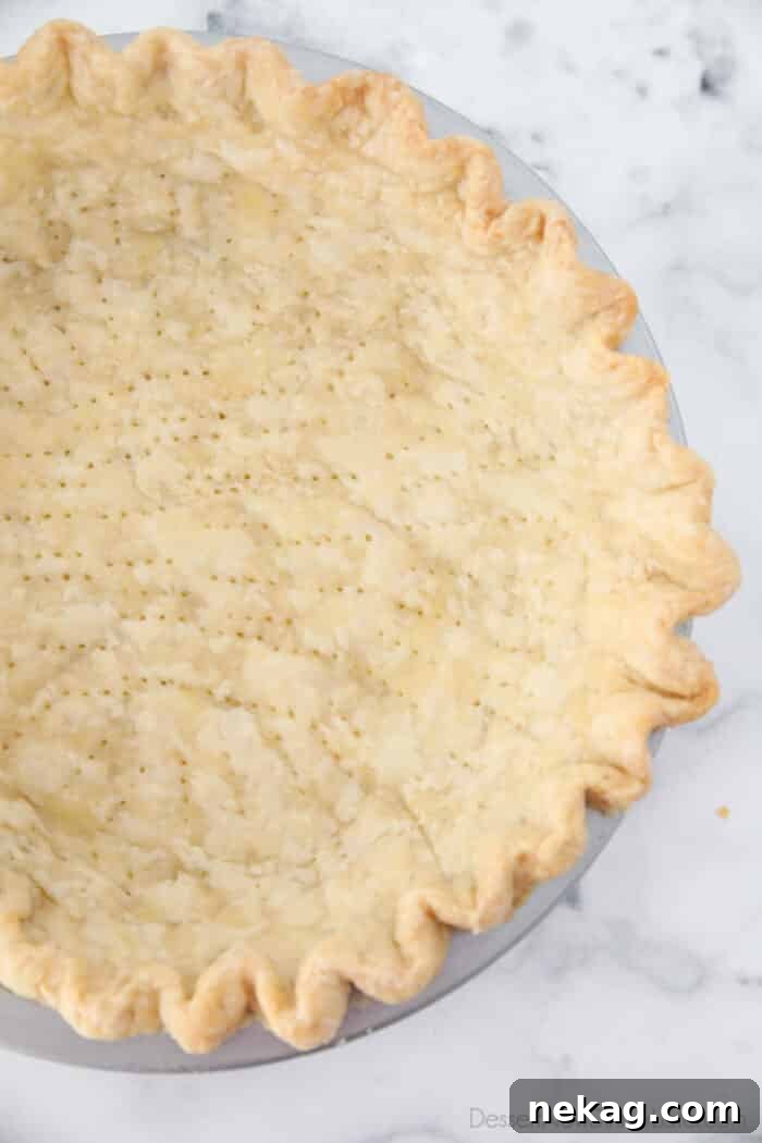 Close up of light golden brown pie crust baked in pan.