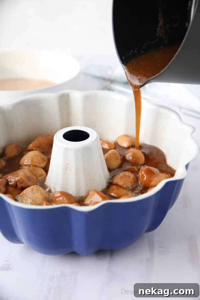 Soft Pull-Apart Monkey Bread Recipe with Video Tutorial 8 Pouring caramel syrup over dough pieces in bundt pan.