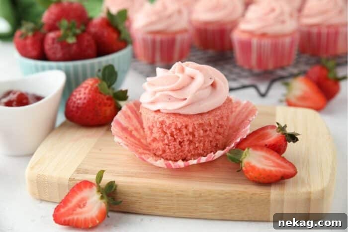 Strawberry Cupcakes Recipe with Step-by-Step Video Tutorial 11 Side view of a strawberry cupcake with the wrapper pulled down to show the texture of the cake.
