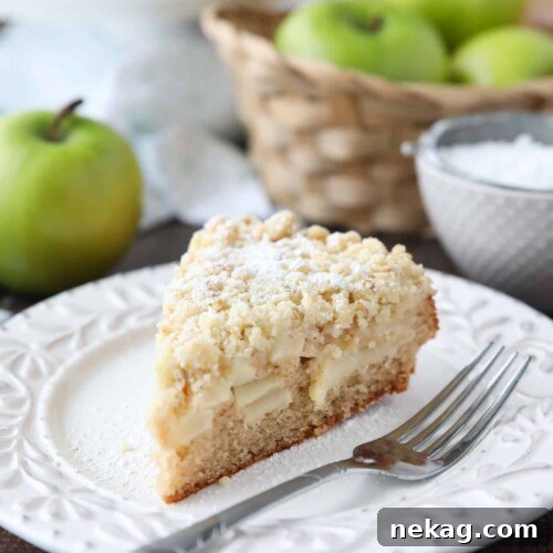Slice of apple cake on a plate with crunchy streusel on top.