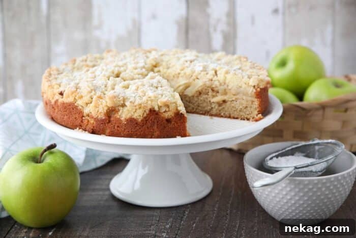 Side view of cake platter with an apple coffee cake and a slice taken out.