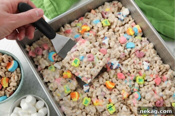 How to Make Irresistible Lucky Charms Treats at Home 7 Scooping a lucky charms marshmallow treat out of the pan.