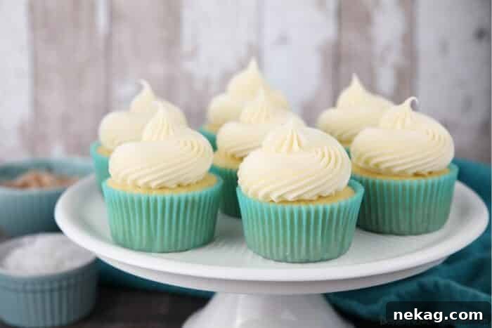 Focus on coconut cream cheese frosting piped high onto cupcakes.