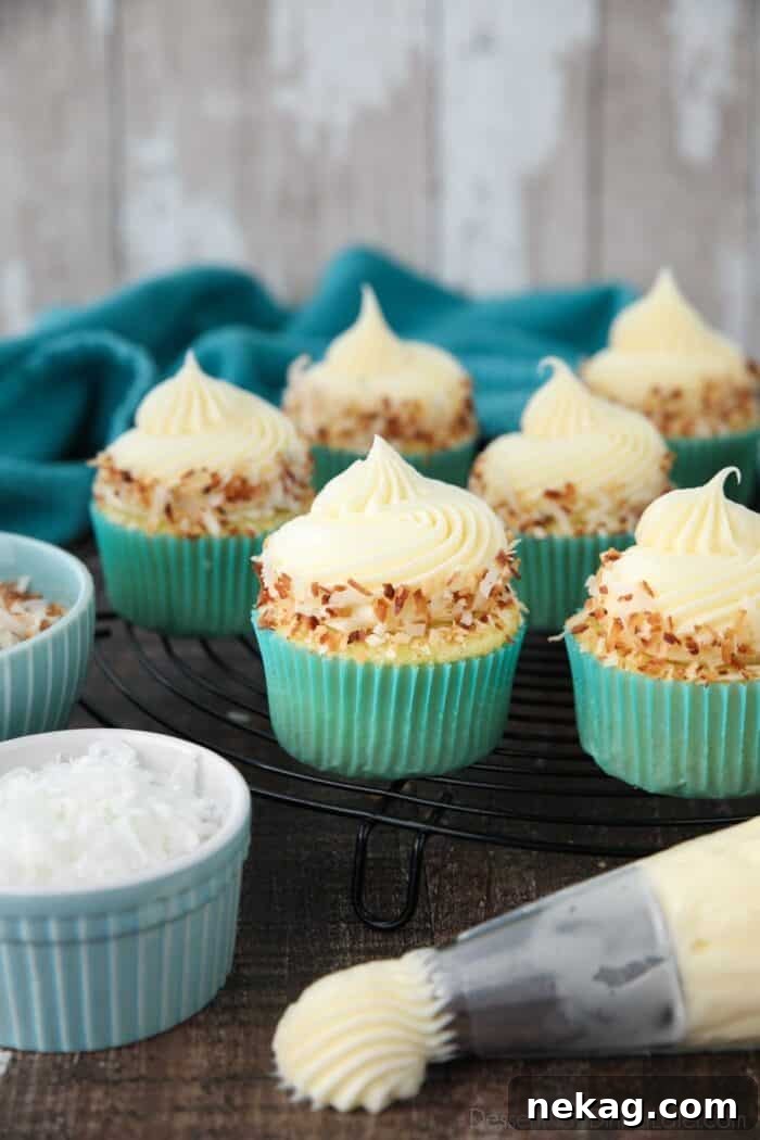 Moist Coconut Cupcakes with Creamy Coconut Frosting 2 Close-up side view of coconut cupcakes with coconut cream cheese frosting and toasted coconut on top.