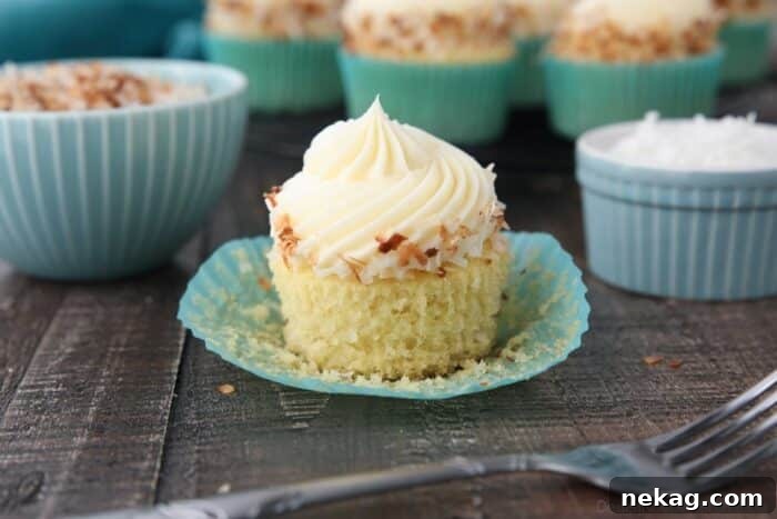 Moist Coconut Cupcakes with Creamy Coconut Frosting 9 Close-up side view of a coconut cupcake with the paper wrapper pulled down.