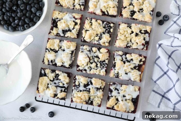 Blueberry Pie Bars Recipe — Rustic Layered Blueberry Dessert 10 Dessert bars with blueberry pie filling sandwiched between a crust and crumb topping with glaze drizzled on top.