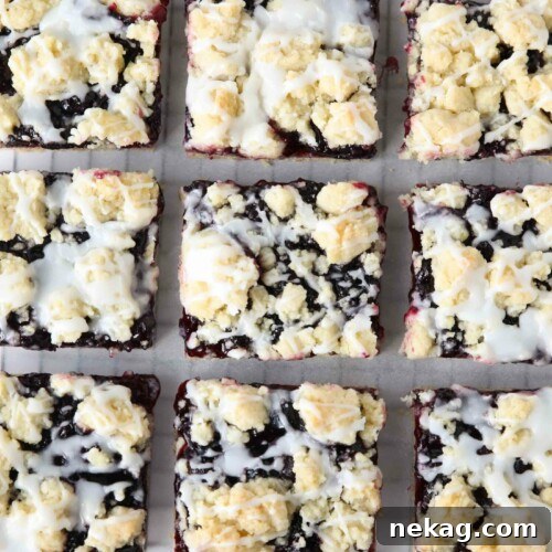 Blueberry Pie Bars Recipe — Rustic Layered Blueberry Dessert 11 Squares of blueberry pie bars with glaze on top resting on a cooling rack.