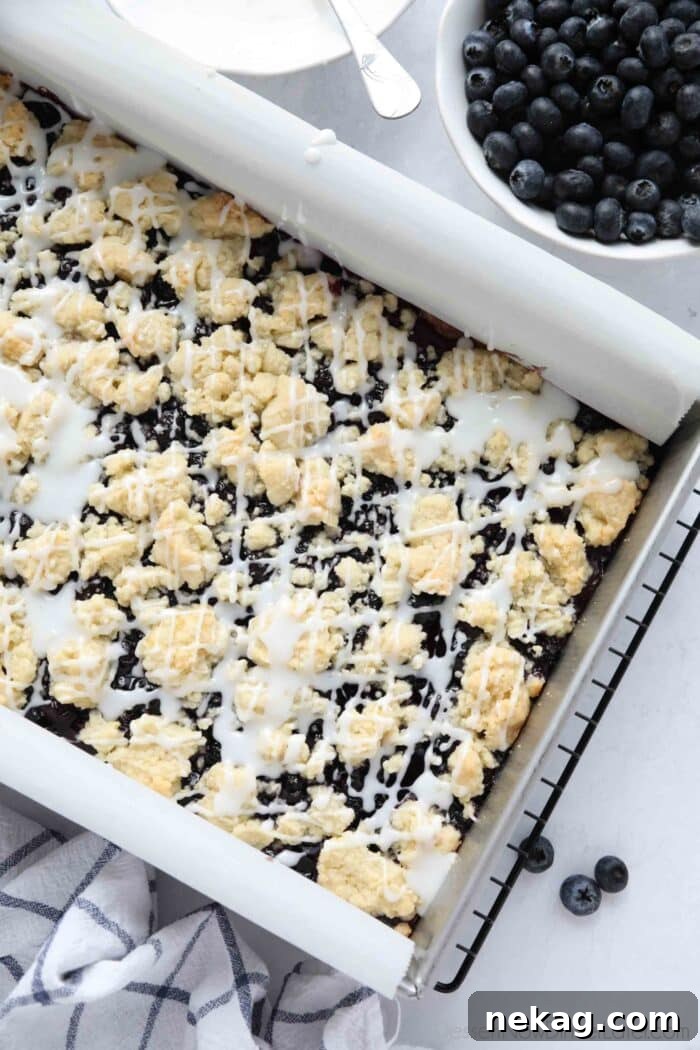 Blueberry Pie Bars Recipe — Rustic Layered Blueberry Dessert 4 Pan of blueberry pie bars with glaze on top.