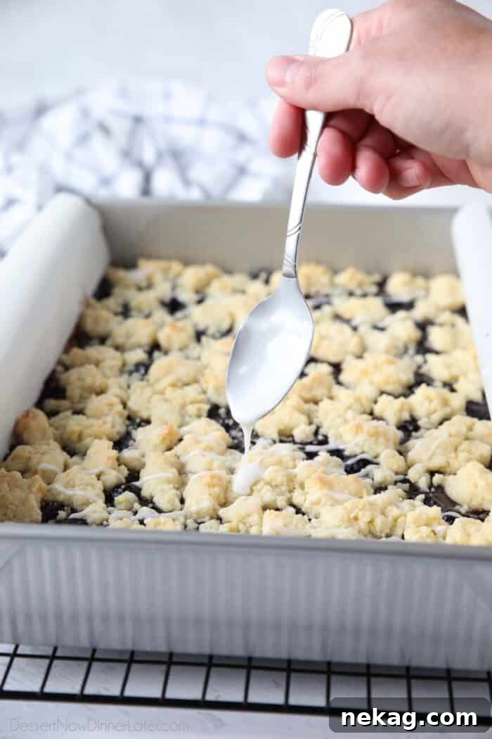 Blueberry Pie Bars Recipe — Rustic Layered Blueberry Dessert 9 Drizzling glaze over baked blueberry bars.
