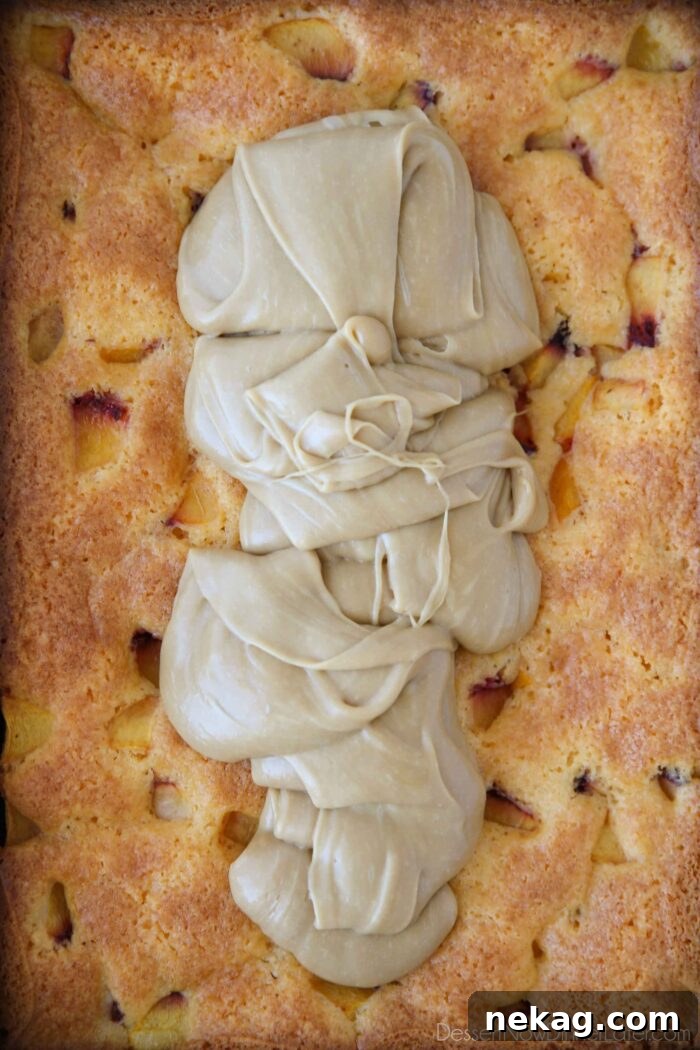 Brown sugar frosting poured on top of a freshly baked peach cake.