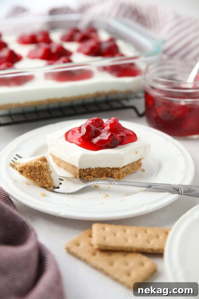 Slice of Cherry Delight on a plate with a fork-full taken out.