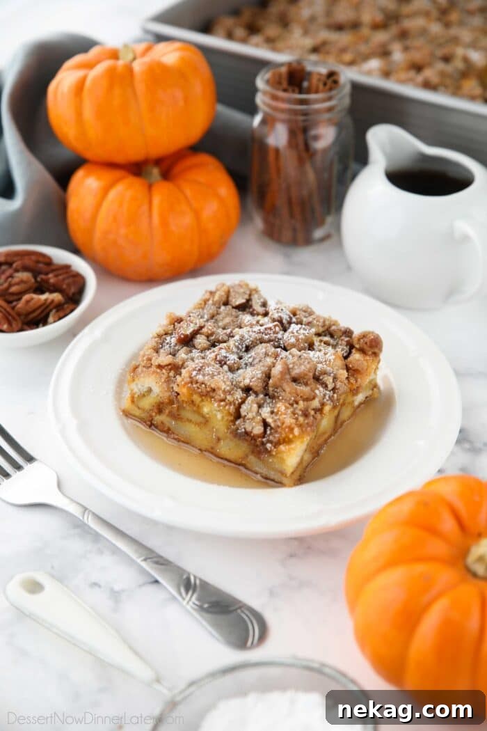 Square piece of pumpkin French toast casserole on a plate with syrup and powdered sugar.