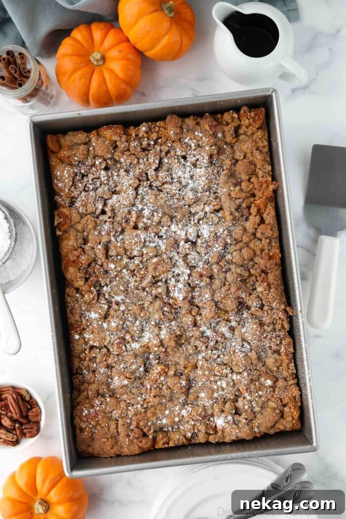 Baked pumpkin French toast casserole in a pan with powdered sugar on top.