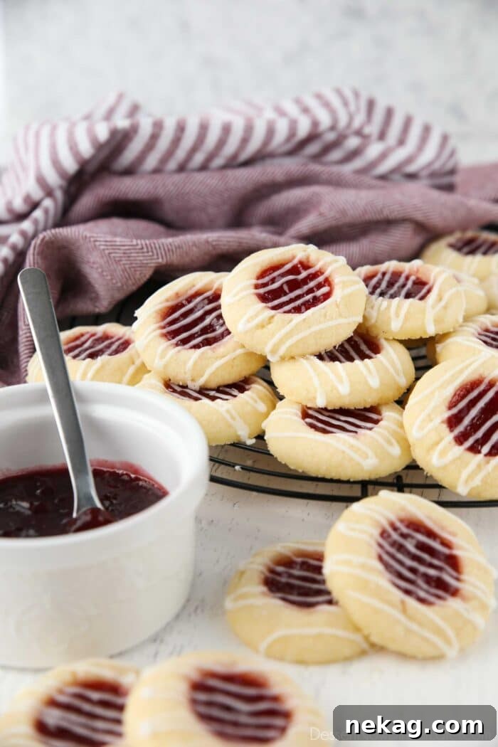 Thumbprint cookies stacked on top of a wire cooling rack.